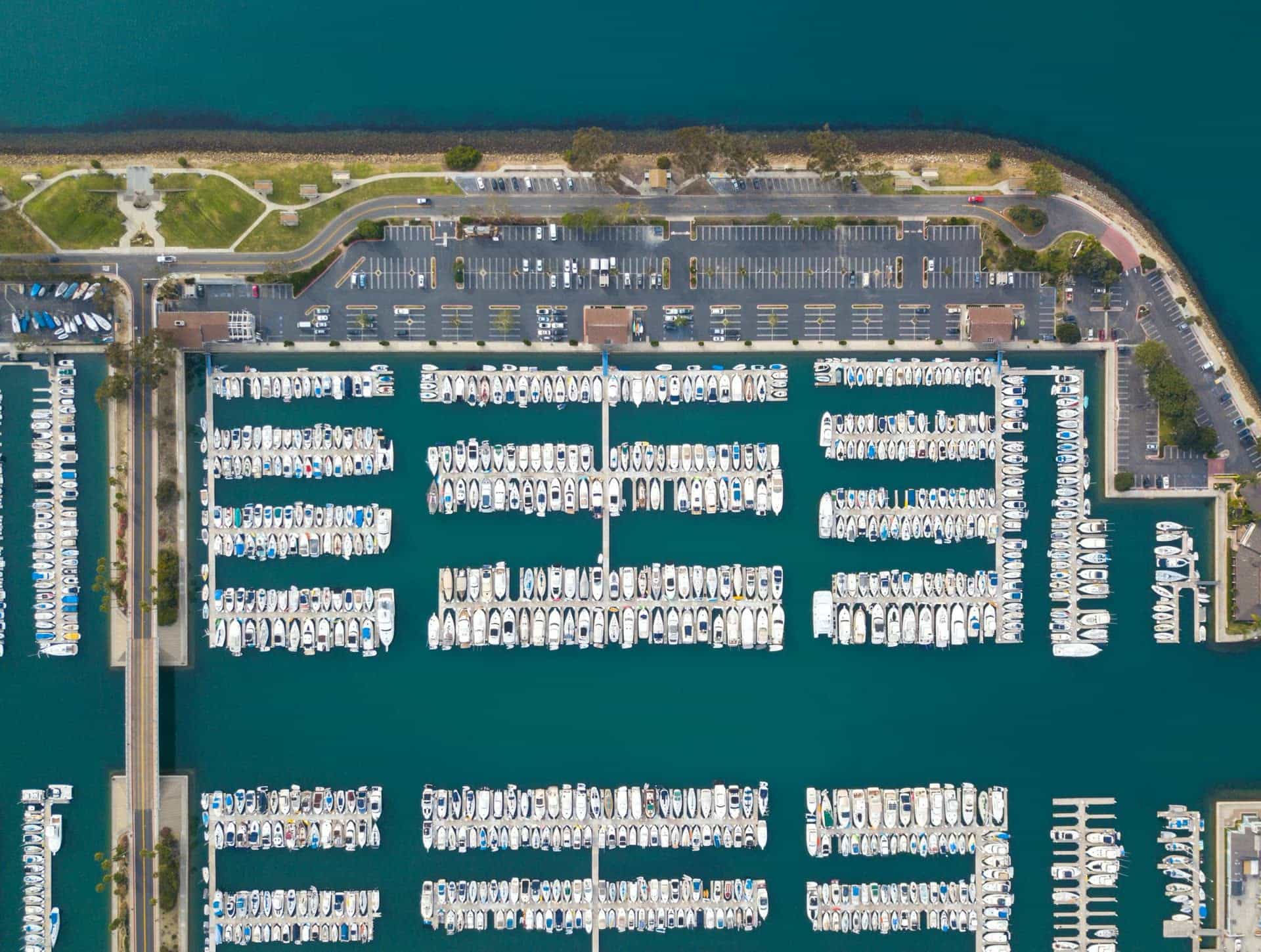 Aerial view of a connected marina with docks, slips, parking, and waterfront access