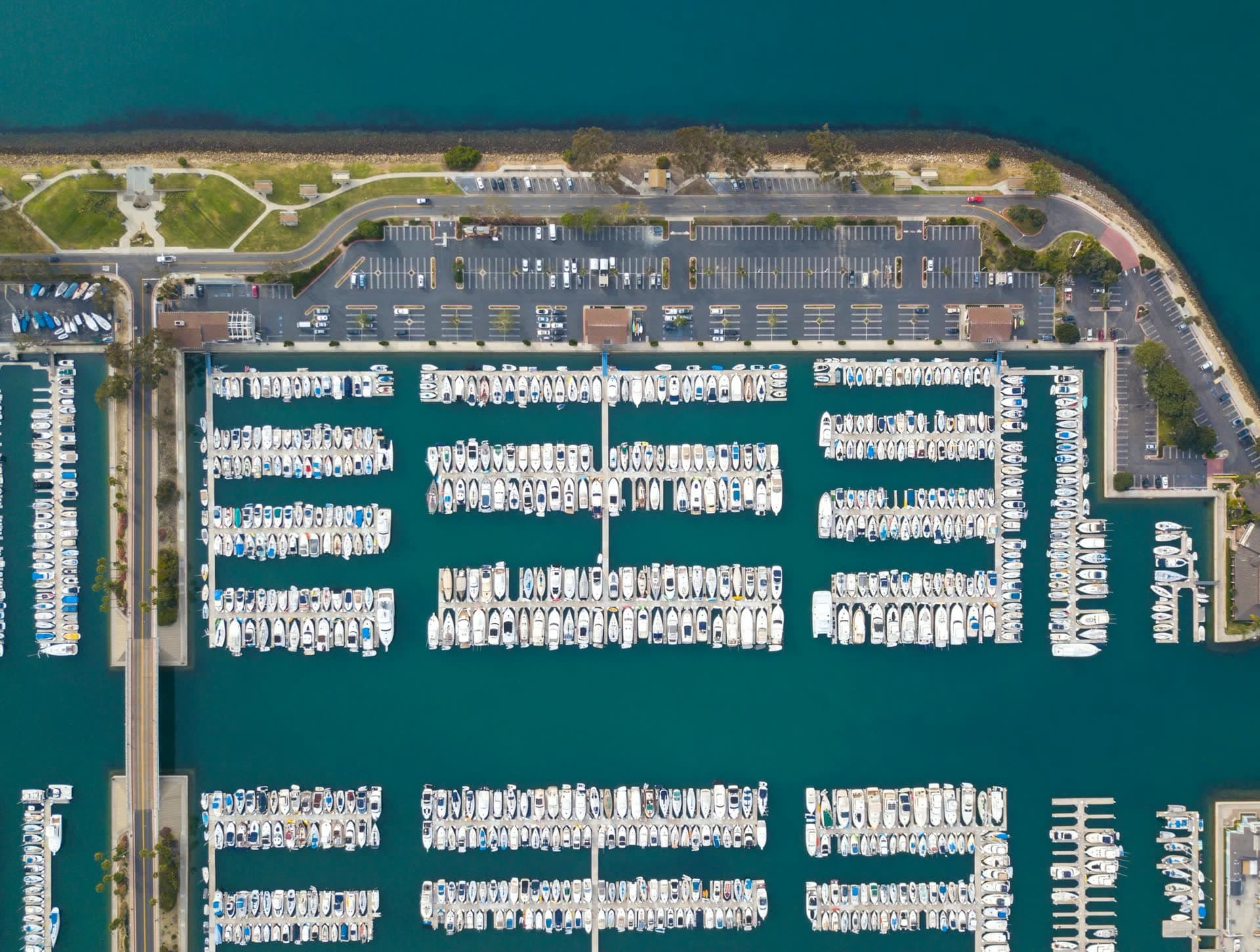 Aerial view of a connected marina with docks, slips, parking, and waterfront access